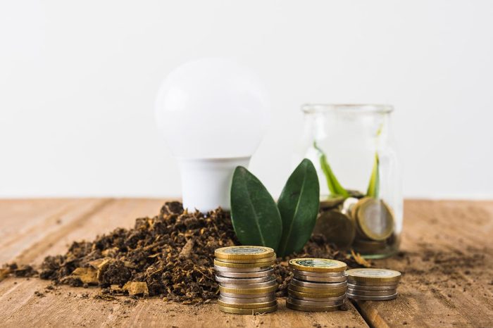 Coins stacked with light bulb and a jar